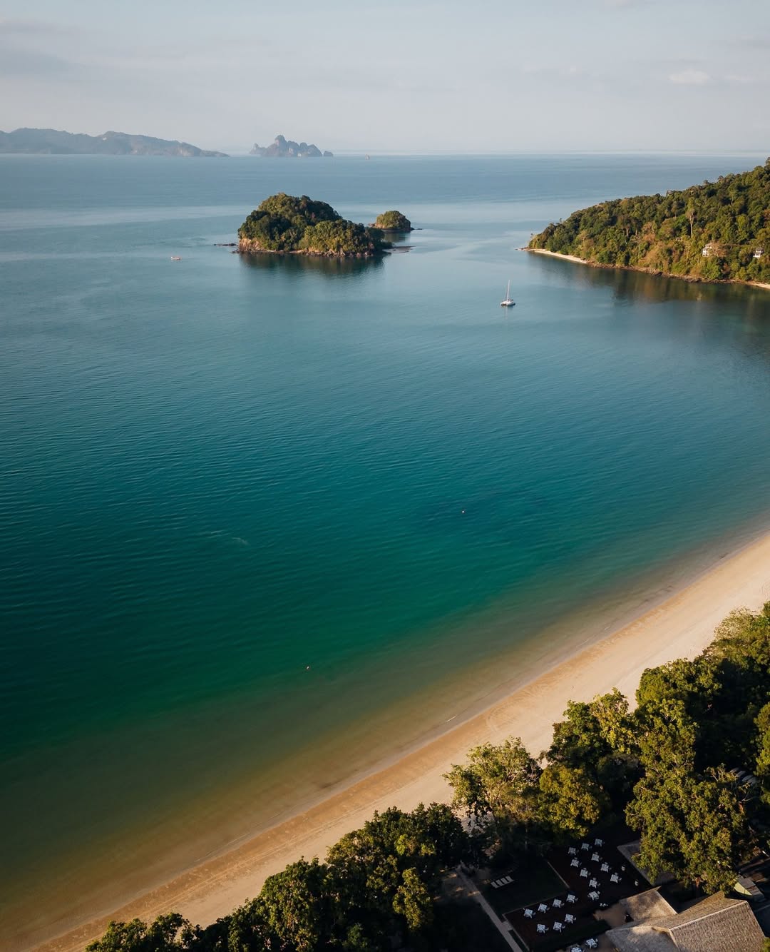 Aerial view of Datai Bay Langkawi with turquoise waters, small islands, and a quiet sandy beach.