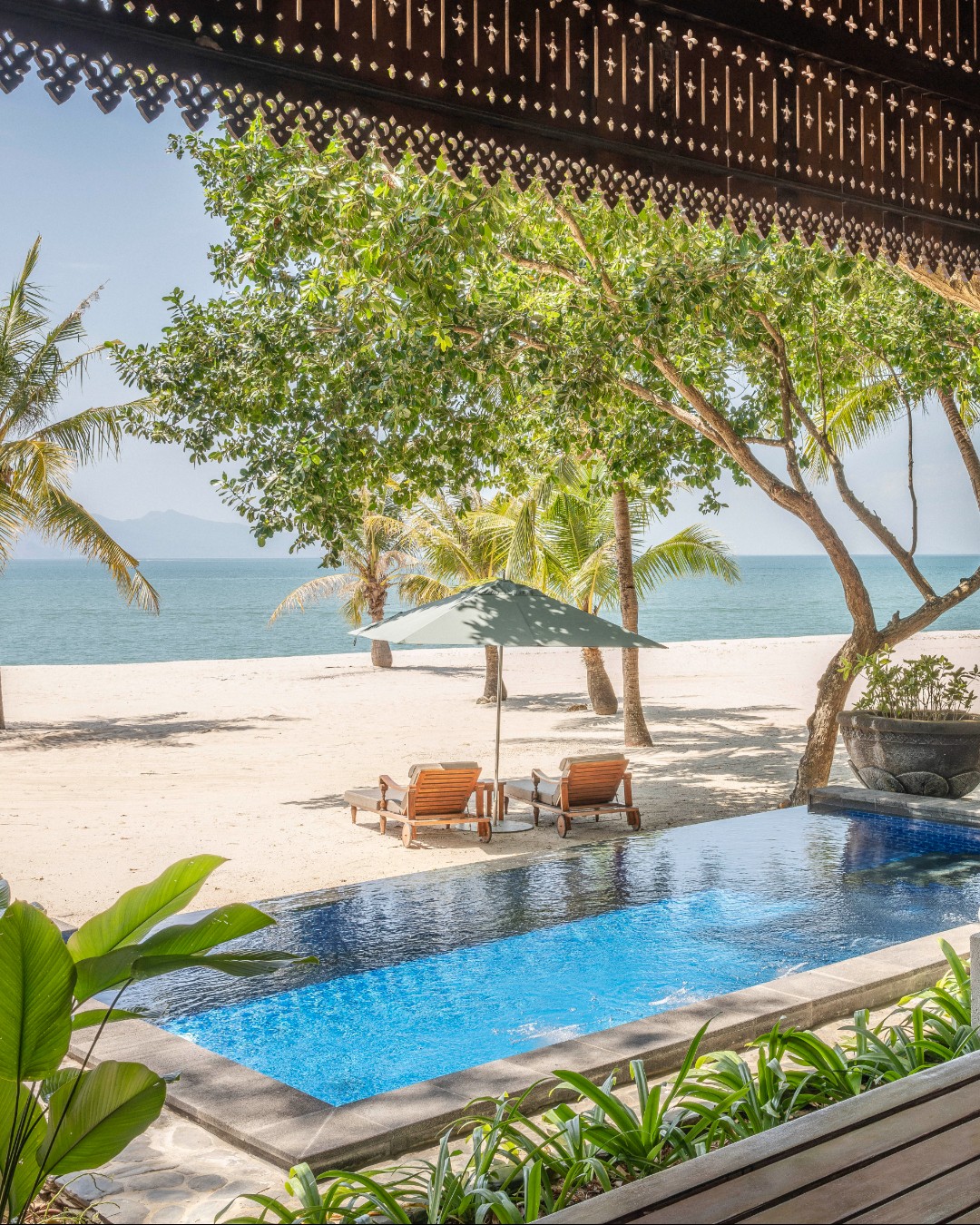 Beachfront private pool villa at Four Seasons Resort Langkawi with sun loungers, palm trees, and direct views of the sandy beach and sea.