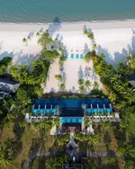 Four Seasons Resort Langkawi beachfront with a central pool, palm trees, and white sandy beach along the sea.