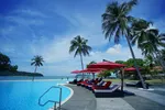 Beachfront pool at Holiday Villa Resort & Beachclub Langkawi with palm trees, red loungers, and views of the sea.
