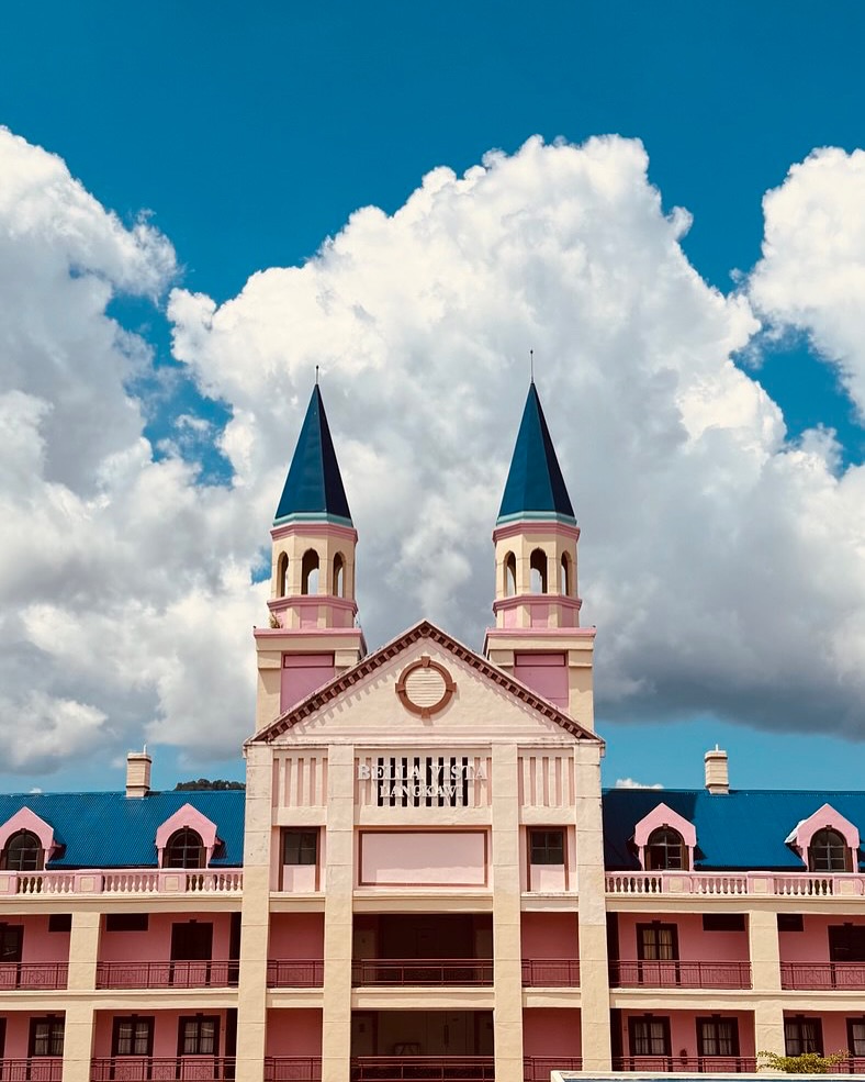 Bella Vista Waterfront Resort Langkawi featuring a distinctive castle-inspired waterfront hotel with twin towers, elegant colonial architecture, and a prime location overlooking Kuah Bay under dramatic blue skies.