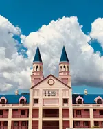 Bella Vista Waterfront Resort Langkawi featuring a distinctive castle-inspired waterfront hotel with twin towers, elegant colonial architecture, and a prime location overlooking Kuah Bay under dramatic blue skies.