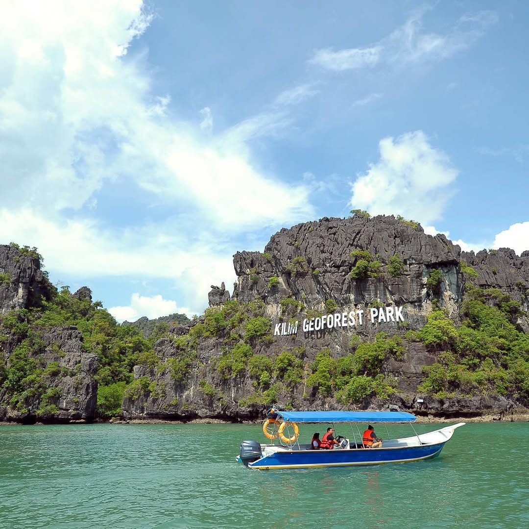 Boat ride at Kilim Geoforest Park Langkawi with limestone cliffs, lush greenery, and turquoise water.