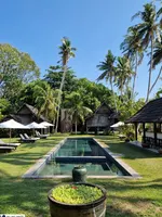 Bon Ton Resort Langkawi featuring traditional Malay wooden villas surrounded by lush tropical gardens, a tranquil rectangular swimming pool, coconut palms, and a peaceful boutique resort atmosphere.