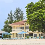 Camar Resort Langkawi featuring a beachfront resort with low-rise tropical accommodations, direct beach access, blue sun loungers and umbrellas, mature shade trees, and a relaxing seaside atmosphere along Pantai Tengah.