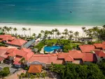Casa del Mar Langkawi featuring an aerial view of a beachfront resort with red-tiled roofs, tropical palm trees, a freeform swimming pool, a white sandy beach, and turquoise waters along Pantai Cenang.