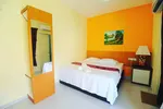 Chenang Inn Langkawi featuring a cozy guest room with a king-size bed, warm orange accent wall, simple wooden furnishings, tiled flooring, and a bright, comfortable atmosphere.