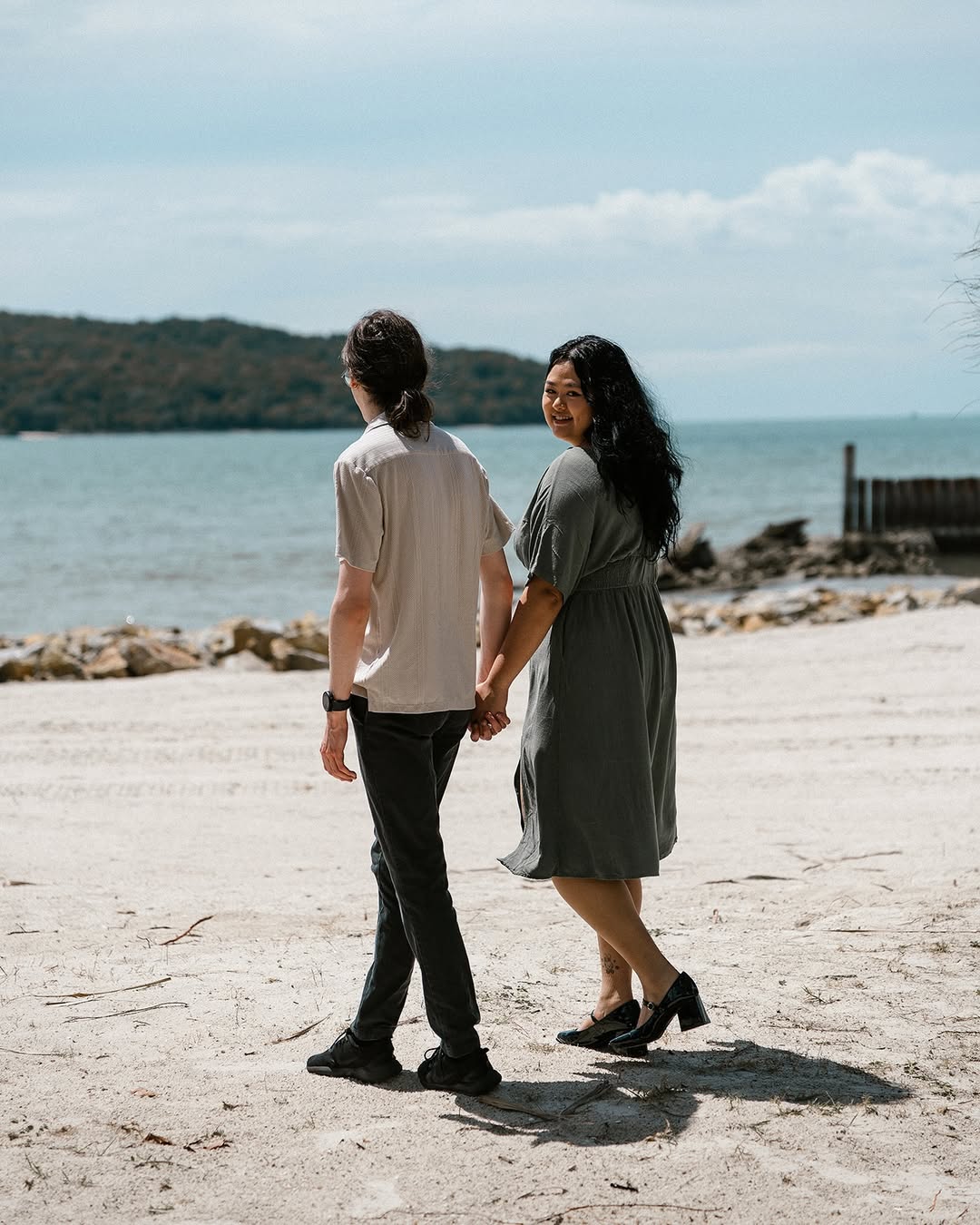 Couple walking hand in hand along the beach at Pelangi Beach Resort Langkawi with the sea in the background.