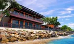 De Baron Resort Langkawi featuring a traditional Malay-inspired beachfront resort with wooden architecture, spacious sea-facing balconies, and a rocky shoreline overlooking the calm waters of Kuah Bay.
