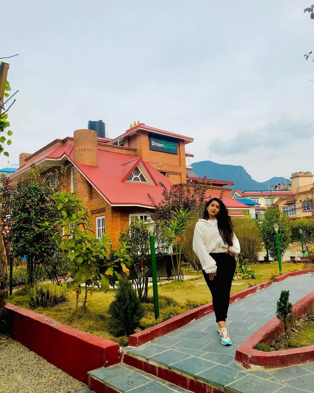 Dream Garden Resort Langkawi featuring charming cottage-style accommodations with red roofs, landscaped gardens, a paved walking path, and scenic mountain views in a peaceful tropical setting.