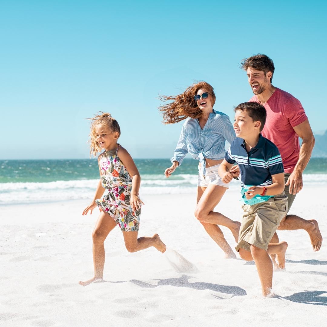 Family running and playing on the beach at Tanjung Rhu Langkawi with the sea and blue sky in the background.