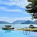 Infinity pool at The Westin Langkawi Resort & Spa overlooking calm sea, distant islands, and a pavilion jetty under a blue sky.