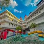 Landcons Hotel Langkawi featuring a family-friendly courtyard with a swimming pool, colorful children's water slides, tropical palm trees, and distinctive castle-inspired architecture with red turret rooftops.