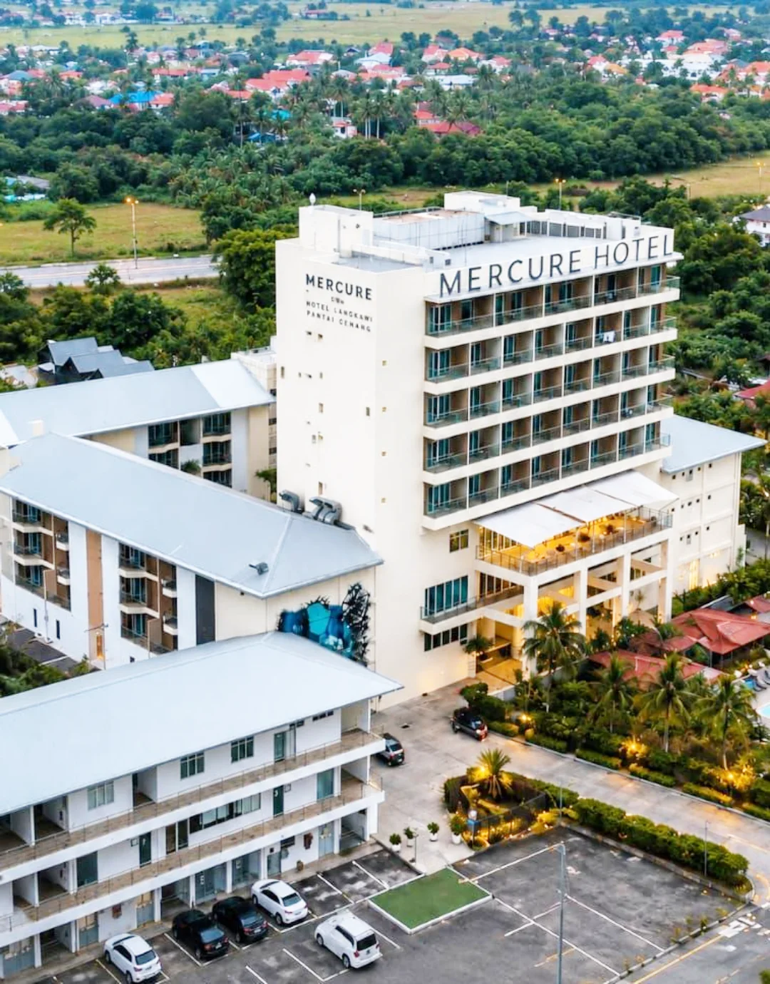 Mercure Langkawi Pantai Cenang featuring a modern mid-rise hotel with contemporary architecture, spacious guest accommodations, landscaped gardens, and panoramic views of Pantai Cenang and the surrounding countryside.