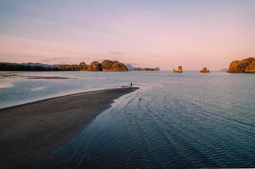 Early morning view at Tanjung Rhu Beach Langkawi with calm waters, sandbanks, and small islands under a soft sunrise sky.