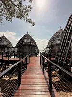 Wooden walkway leading to unique dome-shaped overwater structures with open lattice design, set against the sea in Langkawi.