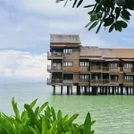 Overwater villas at Langkawi Lagoon Resort standing above the sea with lush greenery in the foreground.
