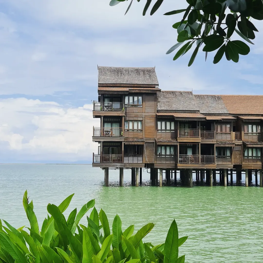 Overwater villas at Langkawi Lagoon Resort standing above the sea with lush greenery in the foreground.