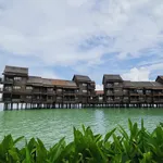 Overwater villas at Langkawi Lagoon Resort set above calm green waters with tropical plants in the foreground.
