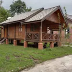 Padimas Villa @ Datai Valley Langkawi featuring a traditional Malay-style wooden villa on stilts with a covered front veranda, rustic timber architecture, and a peaceful garden setting surrounded by lush tropical greenery.