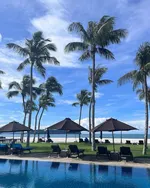 Poolside at Casa del Mar Langkawi with palm trees, sun loungers, and umbrellas overlooking the beach and sea.