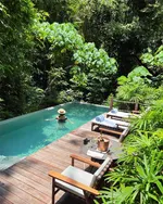 Person relaxing in a private pool at The Datai Langkawi surrounded by dense tropical rainforest and lush greenery.