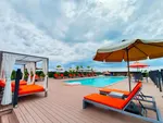 Rooftop pool at The Smith House Langkawi with orange loungers, cabanas, and panoramic sky views.