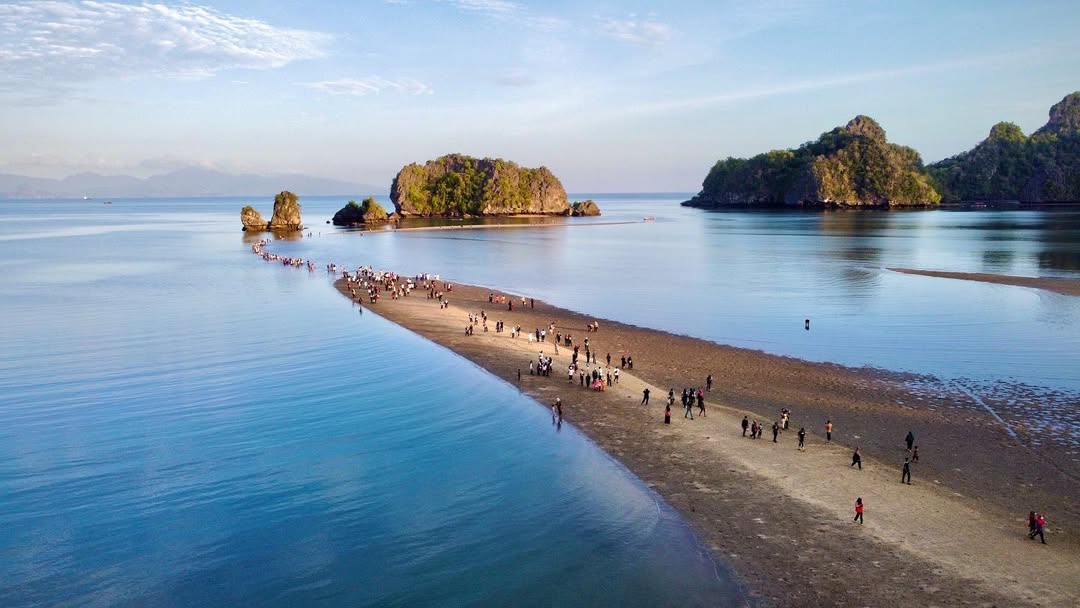 Visitors walking along a sandbar at Tanjung Rhu Langkawi connecting to small islands surrounded by calm blue waters.