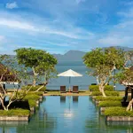 Symmetrical pool at Tanjung Rhu Resort Langkawi overlooking the calm sea, with lounge chairs, an umbrella, and distant mountains.