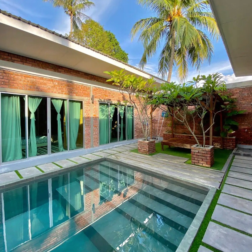 Private pool villa at Tanjung Rhu Langkawi featuring a courtyard pool, brick architecture, greenery, and a shaded seating area.