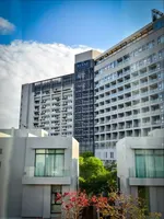 The RIYAZ Lavanya Langkawi featuring a contemporary luxury hotel with modern high-rise architecture, stylish private villas in the foreground, and elegant accommodations in the heart of Pantai Cenang.