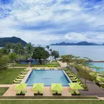 Infinity pool at The Westin Langkawi with green sun loungers, overlooking the calm sea and distant islands under a cloudy sky.