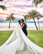 Bride and groom sharing a kiss at The St. Regis Langkawi with palm trees, beach, and sunset sky in the background.