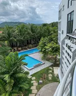 White Lodge Chalet Langkawi featuring a modern hotel overlooking a tropical swimming pool, lush palm gardens, and scenic hillside views, creating a peaceful resort retreat surrounded by nature.